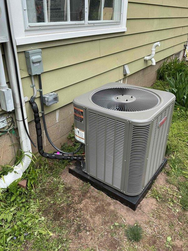 Completed full HVAC system installation including a 70,000 BTU furnace and 2.5-ton air conditioning unit. Installed new furnace in basement utility area with proper venting and condensate drainage using white PVC piping, integrated with existing ductwork system. Positioned outdoor condensing unit on rubber isolation pad at rear of property against exterior wall with pale yellow siding. Ran refrigerant lines and electrical connections from indoor air handler to outdoor unit using proper conduit and line set routing along exterior wall. Installed new dedicated electrical circuit to power system per code requirements. Secured all necessary mechanical and electrical permits prior to installation. Connected condensate drain lines with proper P-trap configuration and routed to exterior discharge point. Verified all electrical connections at outdoor disconnect and meter location. Tested system startup, confirmed proper refrigerant charge, airflow, and temperature differential across evaporato