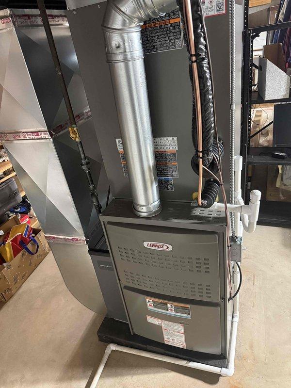 Completed full HVAC system installation including a Lennox 110,000 BTU furnace and 3.5-ton air conditioning unit with right-side configuration in basement utility area. Installed furnace on drain pan with proper condensate drainage using white PVC piping, connected supply and return ductwork to unit top, and routed refrigerant lines with black insulation to outdoor condenser. Reconnected humidifier to new system, established all electrical connections, and verified proper airflow distribution through existing ductwork. All equipment installed per manufacturer specifications with appropriate safety labels visible and accessible for future service.