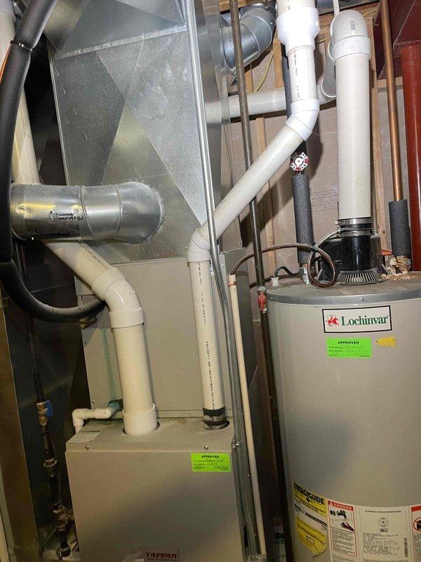 Provided estimate for replacement of non-functional residential furnace originally installed in 2004 and located in basement utility area. Assessed existing HVAC system configuration including gray metal furnace unit, associated ductwork, and white PVC condensate piping integrated with water heater and plumbing infrastructure in confined mechanical space with exposed framing.