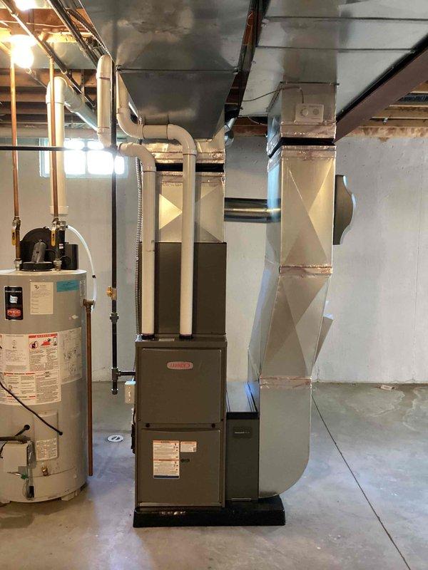 Completed full HVAC system installation including a 70,000 BTU furnace with humidifier and 2-ton air conditioning unit with rear discharge configuration. Installed new furnace in basement mechanical room on equipment platform with proper ductwork connections and sheet metal transitions to existing distribution system. Mounted outdoor condensing unit on concrete pad against exterior wall with refrigerant line set routed up vinyl siding, secured with appropriate brackets and insulation. Installed electrical disconnect box and completed all electrical connections per code requirements. Reconnected all necessary plumbing and drainage lines to equipment. System was tested for proper operation, refrigerant charge verified, and all safety controls confirmed functional. Installation completed under mechanical permit as specified.