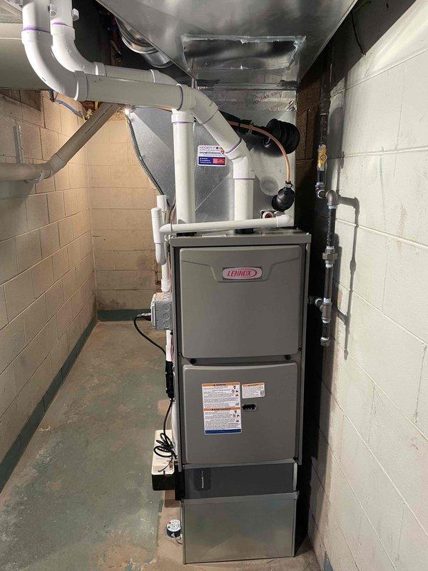 Completed full HVAC system installation in basement utility room, including Lennox 70,000 BTU furnace and 2.5-ton air conditioning unit with rear discharge configuration. Installed new electrical circuit to service equipment per code requirements. Secured mechanical and electrical permits prior to installation. Mounted furnace against existing concrete block wall with proper clearances maintained throughout. Connected white PVC venting pipes from furnace to overhead exhaust system with appropriate pitch for condensate drainage. Installed condensate pump at base of system to handle moisture removal. Ran refrigerant lines from outdoor condensing unit to indoor coil with proper insulation applied. Fabricated and installed sheet metal ductwork transition plenum connecting furnace to existing distribution system. Secured flexible duct connector to accommodate vibration isolation. Made all electrical connections including power supply and control wiring. Tested system startup sequence, verif