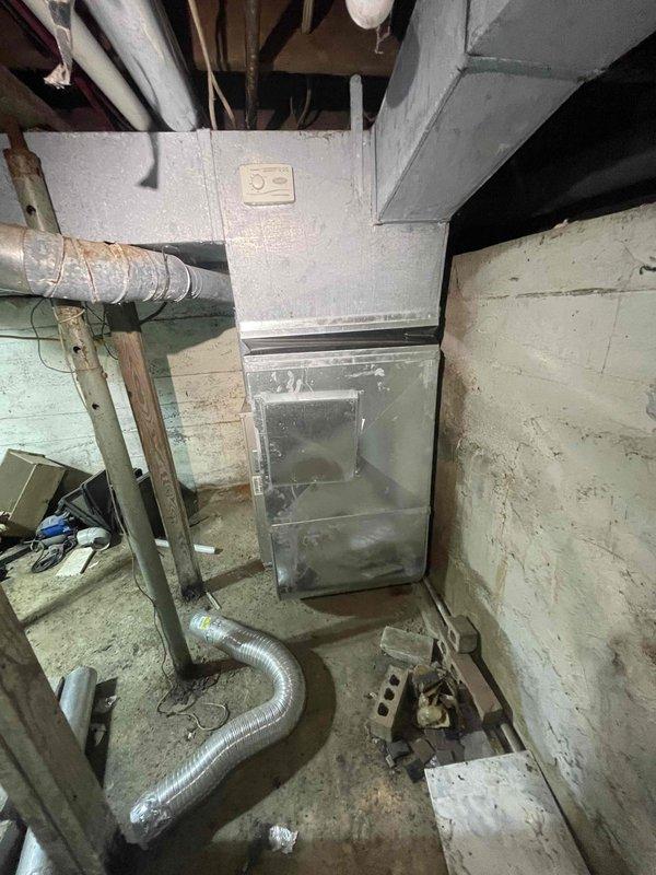Conducted on-site evaluation for air conditioning system installation at property currently without cooling equipment. Assessed existing furnace infrastructure in basement utility area, noting aged mechanical room with vertical furnace unit, metallic ductwork, and available electrical service. Evaluated installation requirements including outdoor condenser placement, refrigerant line routing, condensate drainage integration with existing PVC plumbing system, and electrical supply compatibility. Documented existing HVAC infrastructure including furnace configuration, duct system layout, and basement mechanical space constraints. Photographed installation area to determine equipment sizing requirements and identify any structural or accessibility considerations for new AC system integration with current heating equipment. Property inspection completed in preparation for comprehensive replacement estimate.