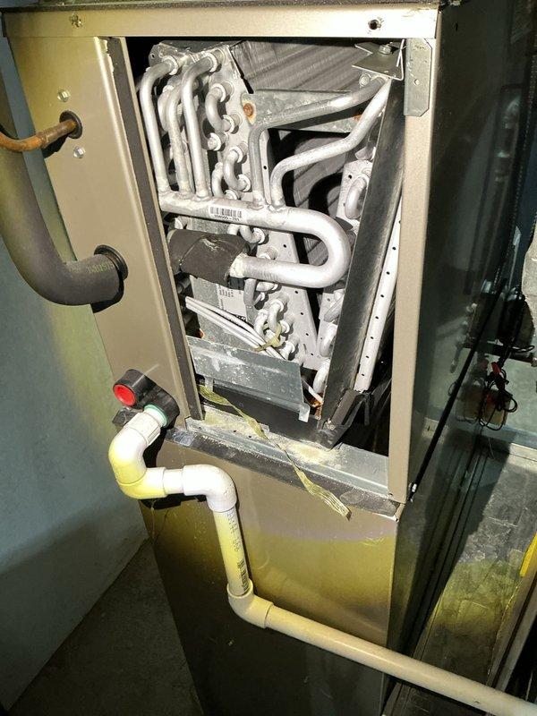 Completed annual cooling maintenance on residential split HVAC system. Performed comprehensive inspection of vertical furnace unit and evaporator coil assembly, documenting equipment condition through photographs. Verified proper operation of A-frame coil configuration, checked condensate drain lines and trap assembly for proper drainage, and inspected all PVC piping connections. Examined ductwork mounting and securing hardware, confirmed electrical connections, and assessed overall system functionality. All components found operational with age-appropriate wear noted on coil surfaces and minor discoloration on drain piping. System cleared for continued service.