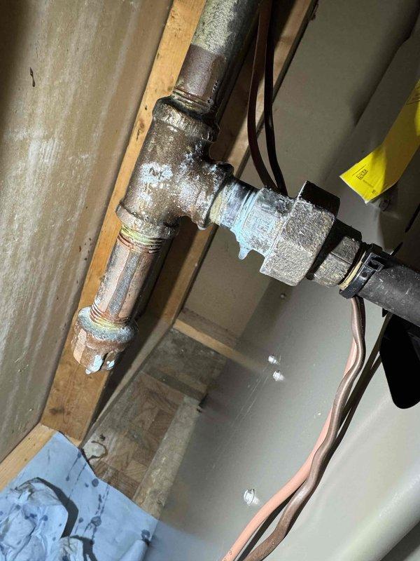Responded to no-heat call on 4-year-old furnace where utility company had shut off gas supply due to detected leak. Upon arrival, performed comprehensive visual inspection of gas piping system and identified significant corrosion and rust deterioration on multiple threaded pipe connections at T-junction near furnace inlet. Found compromised pipe integrity with flaking surface degradation on galvanized steel piping, creating unsafe conditions for gas service. Documented corroded sections with photographs showing brownish oxidation, worn threading, and structural weakness at connection points. Verified red-handled ball valve operation and traced copper supply lines to determine extent of affected piping. Advised immediate replacement of corroded gas piping sections before system could be safely returned to service, as current pipe condition poses continued leak risk and fails to meet code requirements for gas appliance connections.