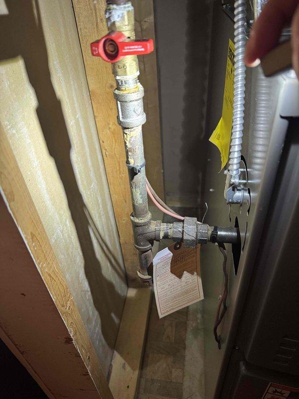 Responded to no-heat call on 4-year-old furnace where utility company had shut off gas supply due to detected leak. Upon arrival, performed comprehensive visual inspection of gas piping system and identified significant corrosion and rust deterioration on multiple threaded pipe connections at T-junction near furnace inlet. Found compromised pipe integrity with flaking surface degradation on galvanized steel piping, creating unsafe conditions for gas service. Documented corroded sections with photographs showing brownish oxidation, worn threading, and structural weakness at connection points. Verified red-handled ball valve operation and traced copper supply lines to determine extent of affected piping. Advised immediate replacement of corroded gas piping sections before system could be safely returned to service, as current pipe condition poses continued leak risk and fails to meet code requirements for gas appliance connections.