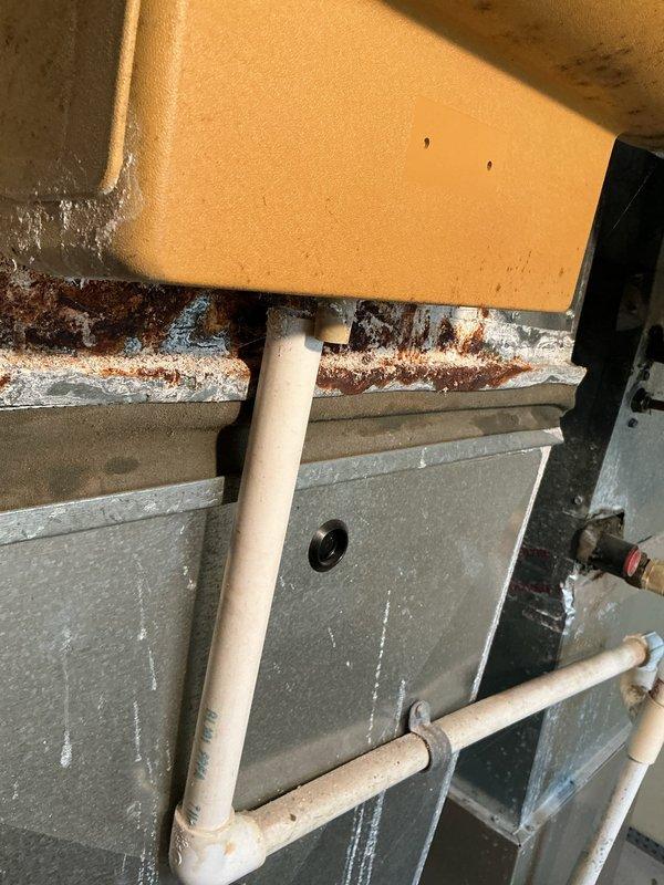 Responded to callback for furnace water leak. Upon inspection, discovered extensive rust and corrosion on horizontal condensate drain components and air handler housing. Documented significant oxidation on metal brackets and deterioration at foam insulation interface points. Heavy rust accumulation and mineral deposits indicate prolonged moisture exposure from condensate system failure. Photographed corroded areas including drain line connections and compromised metal surfaces for warranty documentation and further assessment of unit integrity.