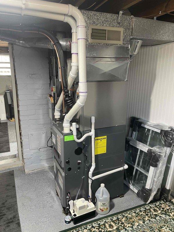 Completed full installation of 2-ton air conditioning system with matching evaporator coil in residential basement mechanical room. Obtained mechanical and electrical permits prior to installation, then positioned and connected outdoor condensing unit on right side of property with proper refrigerant line routing. Indoor evaporator coil was installed above existing furnace unit with insulated copper refrigerant lines connected to outdoor unit. All electrical connections completed per code requirements, condensate drainage system installed with pump for proper moisture removal, and system startup performed with refrigerant charge verification. Unit tested for proper operation and all components functioning within manufacturer specifications.