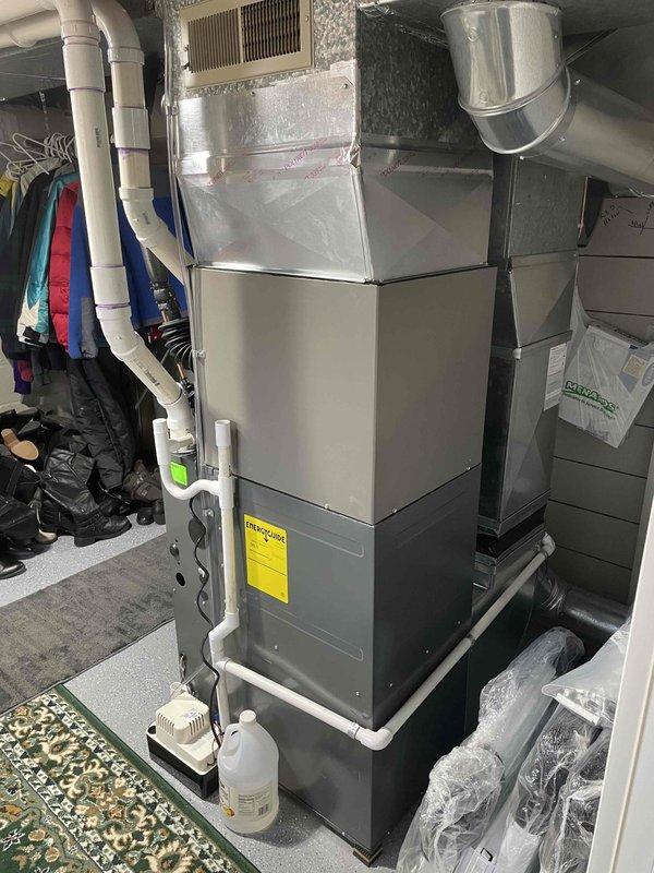 Completed full installation of 2-ton air conditioning system with matching evaporator coil in residential basement mechanical room. Obtained mechanical and electrical permits prior to installation, then positioned and connected outdoor condensing unit on right side of property with proper refrigerant line routing. Indoor evaporator coil was installed above existing furnace unit with insulated copper refrigerant lines connected to outdoor unit. All electrical connections completed per code requirements, condensate drainage system installed with pump for proper moisture removal, and system startup performed with refrigerant charge verification. Unit tested for proper operation and all components functioning within manufacturer specifications.