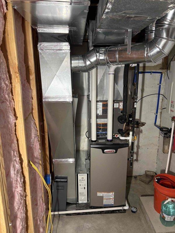 Completed full HVAC system installation in basement utility room, including 70,000 BTU furnace and 2-ton air conditioning unit. Installed new gray furnace unit with proper venting using white PVC intake and exhaust pipes, connected metallic ductwork distribution system with rigid and flexible components, and reconnected all necessary gas lines, copper plumbing, and electrical wiring. System installed per mechanical permit specifications with front-facing configuration, all manufacturer labels and safety warnings properly displayed, and equipment positioned for optimal access and serviceability.