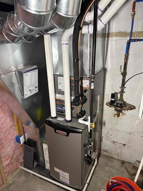 Completed full HVAC system installation in basement utility room, including 70,000 BTU furnace and 2-ton air conditioning unit. Installed new gray furnace unit with proper venting using white PVC intake and exhaust pipes, connected metallic ductwork distribution system with rigid and flexible components, and reconnected all necessary gas lines, copper plumbing, and electrical wiring. System installed per mechanical permit specifications with front-facing configuration, all manufacturer labels and safety warnings properly displayed, and equipment positioned for optimal access and serviceability.