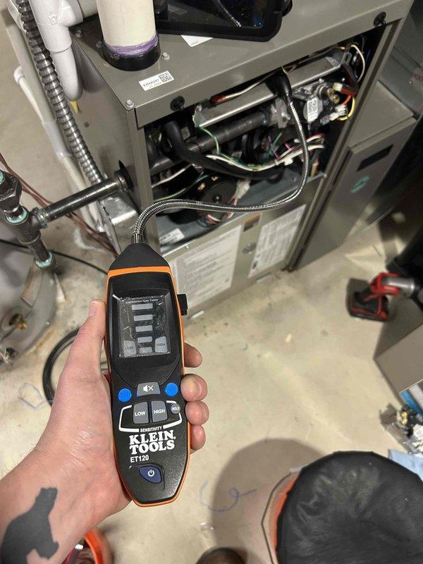 Responded to emergency service call for reported gas odor from 3-year-old furnace in basement that had been shut down for safety. Performed comprehensive leak detection inspection using electronic refrigerant/gas leak detector on furnace cabinet, heat exchanger, gas valve assembly, and all gas piping connections. Removed front access panel and thoroughly inspected internal components including blower motor, wiring harnesses, burner assembly, and flue piping. Checked all PVC vent pipe connections and condensate drain trap for proper seal integrity. Verified gas supply line connections and flexible conduit routing. All components inspected showed no evidence of gas leaks or combustion issues. Unit remains under parts and labor warranty coverage.