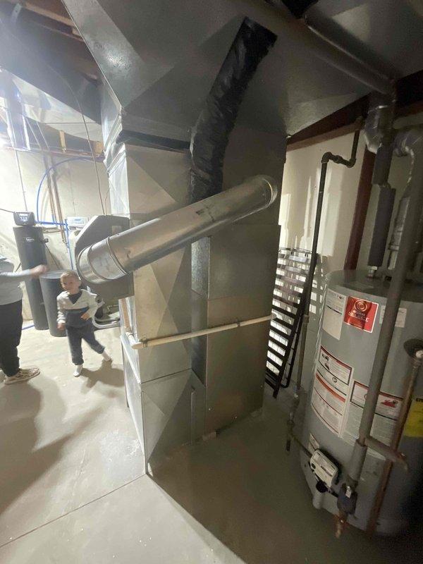 Completed comprehensive estimate for full HVAC system replacement at residential property with 23-year-old original equipment. Assessed existing furnace in basement utility area with metal ductwork and air handler configuration, along with outdoor cylindrical air conditioning unit mounted on river rock base against exterior wall with associated electrical connections and copper refrigerant lines. Customer requested expedited replacement timeline for both heating and cooling systems prior to summer season, with both units having reached end of expected service life.
