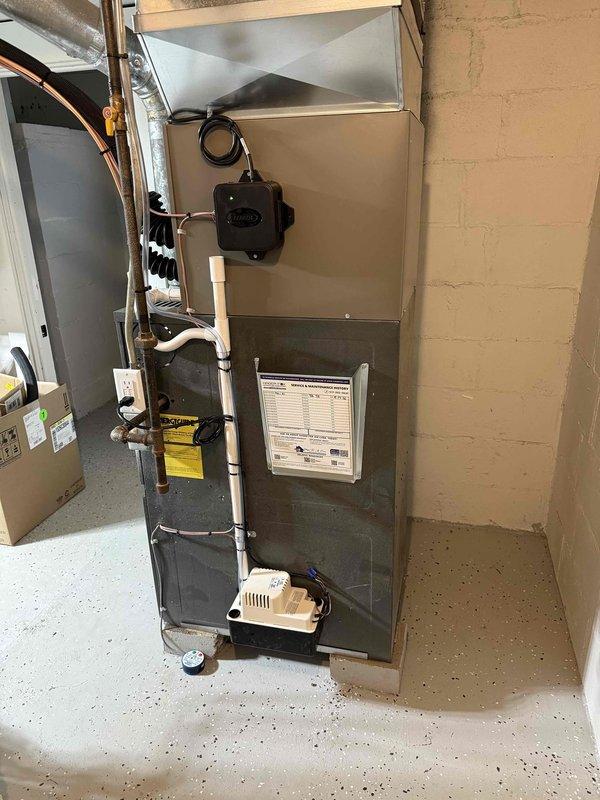 Successfully installed a complete 2-ton air conditioning system with matching evaporator coil on a Goodman furnace unit in the basement mechanical room. The installation included proper refrigerant line connections on the left side of the unit, electrical hookups with conduit and controls mounted to the wall, condensate drainage system with PVC piping and pump, and metallic flex ductwork connected to the furnace plenum. All mechanical and electrical permits were obtained, system was tested and operational, and installation photographs were documented for record purposes.