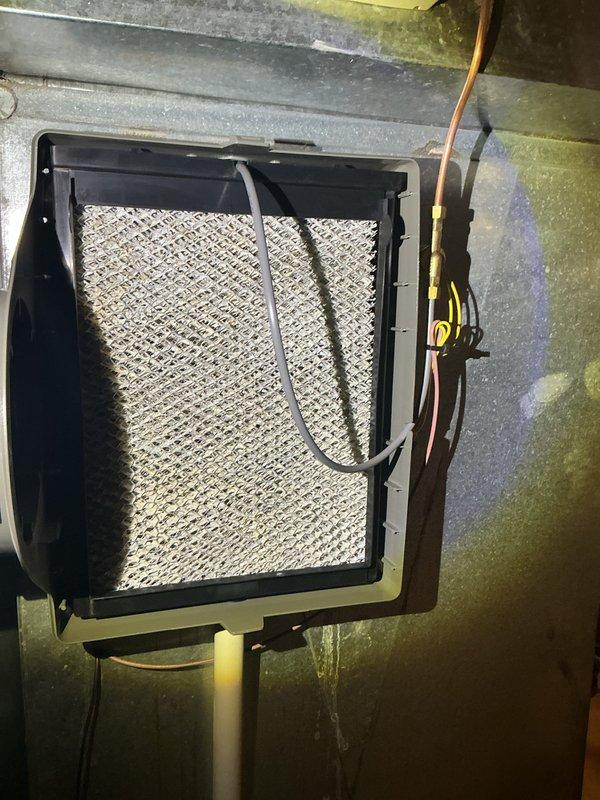 Completed annual cooling maintenance on residential HVAC system. Inspected air handler unit and filter assembly, noting pleated filter in serviceable condition within hinged frame housing. Observed condensate drain lines and PVC piping routing properly from equipment. System components including ductwork, electrical connections, and sensor wiring were visually inspected and found operational, though some dust accumulation and minor discoloration noted on duct surfaces typical of normal system aging.