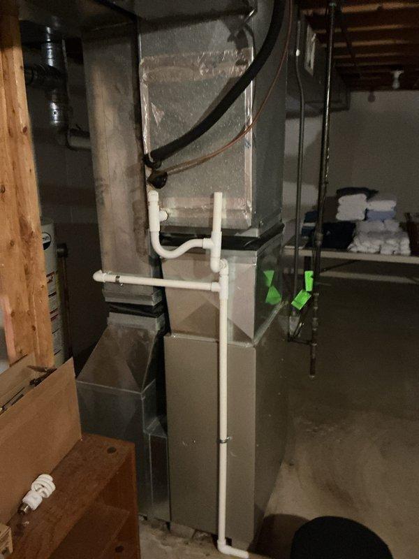 Completed annual cooling maintenance on residential HVAC system. Inspected air handler unit and filter assembly, noting pleated filter in serviceable condition within hinged frame housing. Observed condensate drain lines and PVC piping routing properly from equipment. System components including ductwork, electrical connections, and sensor wiring were visually inspected and found operational, though some dust accumulation and minor discoloration noted on duct surfaces typical of normal system aging.