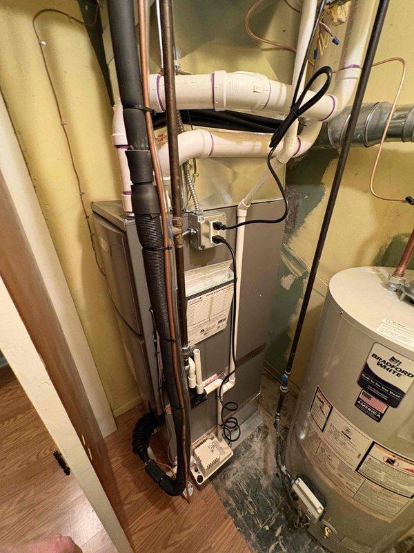 Completed full HVAC system installation in residential utility closet including 70,000 BTU gas furnace, 2-ton rear-discharge air conditioning unit, hot water heater, and whole-home humidifier. Installed and secured all equipment in confined space with proper clearances, ran and connected copper refrigerant lines, installed PVC condensate drainage system, and routed flexible ductwork for air distribution. Mounted Healthy Climate humidifier to supply plenum, installed water supply lines with proper insulation, and completed all electrical connections. Secured equipment with appropriate mounting brackets and metal strapping, reconnected existing utilities, and verified proper operation of all installed systems.