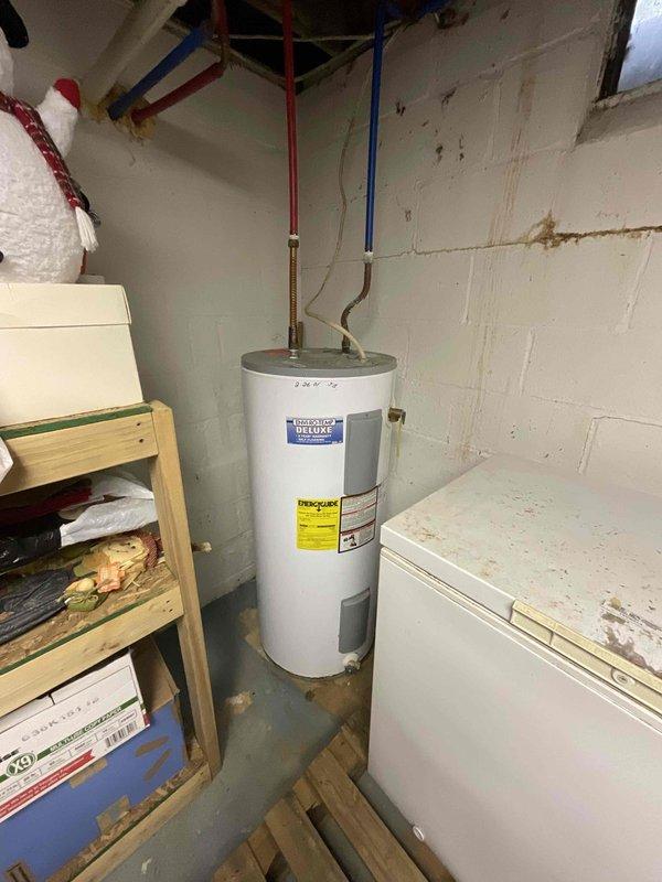 Provided comprehensive estimate for complete HVAC system replacement in basement location, including 25-year-old furnace, water heater tank, and associated electrical upgrades. Assessed existing operational equipment and documented current conditions of beige furnace unit with metallic ductwork and white cylindrical water heater with visible moisture staining at base, noting copper flex connectors and supply piping configuration. Recommended full system replacement to address age-related efficiency concerns and ensure code-compliant electrical service for new equipment installation.