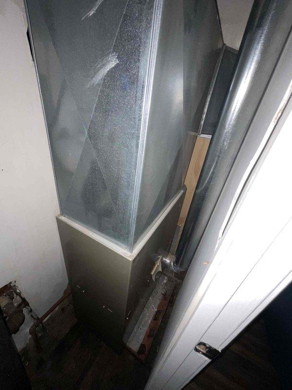 Completed estimate for full HVAC system replacement at residential property. Assessed existing furnace of unknown age located in confined mechanical space with tight clearance and evaluated property currently lacking air conditioning system. Documented equipment condition showing significant age-related wear, dust accumulation, and aging metal cabinet housing. Evaluated installation space constraints including narrow hallway access with louvered ventilation door and limited attic or mechanical closet clearance for future equipment replacement. Provided replacement options for complete heating and cooling system installation to address immediate need for air conditioning addition and aging furnace replacement.