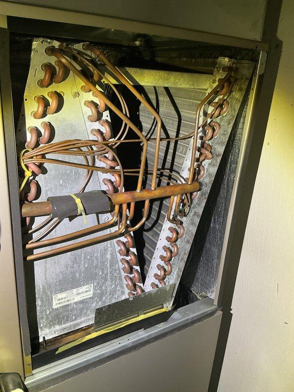 Completed annual cooling maintenance on HVAC system. Inspected evaporator coil and found heavy accumulation of dust and debris throughout the fin assembly, significantly restricting airflow. Documented condition of copper refrigerant lines showing normal oxidation patina, verified all tube connections and brazed joints for integrity, and photographed internal components including coil assembly and associated piping for maintenance records.