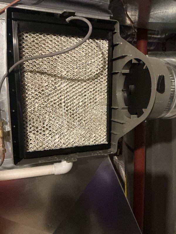 Performed annual HVAC maintenance on Lennox forced-air system, including inspection of evaporative humidifier pad filter which showed dust accumulation and discoloration. Documented existing system condition and noted requirement for 45-foot by 4-inch chimney liner installation to be coordinated with future service work.