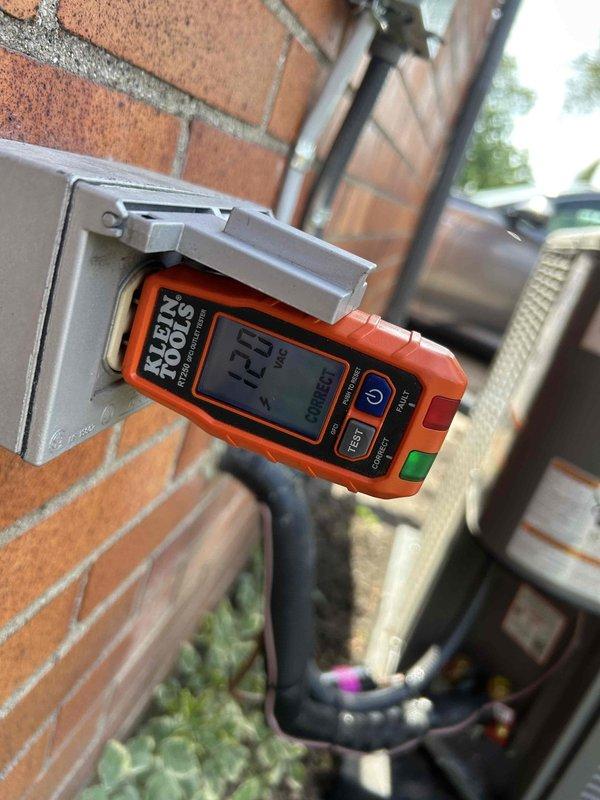 Responded to callback for recently installed 70K BTU furnace and 2.5-ton A/C system regarding thermostat not allowing cooling mode selection and missing outdoor GFCI receptacle. Installed weatherproof GFCI outlet on exterior brick wall near Lennox condenser unit and verified proper operation with electrical testing meter showing 123V. Corrected thermostat wiring and configuration to restore cooling functionality, confirmed system operation in all modes.
