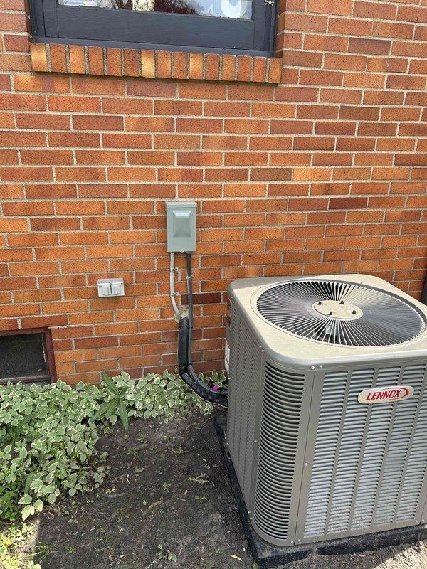 Responded to callback for recently installed 70K BTU furnace and 2.5-ton A/C system regarding thermostat not allowing cooling mode selection and missing outdoor GFCI receptacle. Installed weatherproof GFCI outlet on exterior brick wall near Lennox condenser unit and verified proper operation with electrical testing meter showing 123V. Corrected thermostat wiring and configuration to restore cooling functionality, confirmed system operation in all modes.