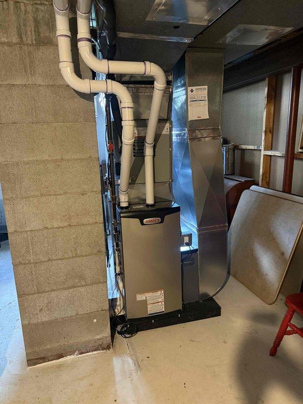 Completed installation of Lennox 70,000 BTU furnace in basement mechanical room. Unit mounted on platform with PVC venting routed overhead and connected to existing ductwork. All mechanical connections completed and system reconnected to operational status.