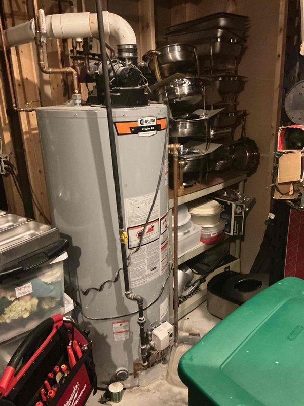 Responded to service call for water heater leaking from pipe connection. Upon arrival, performed visual inspection of tanked water heater unit located in basement utility area. Identified active leak originating from pipe fitting at top of tank. Assessed water heater condition and examined all visible plumbing connections, including copper and PVC piping. Documented equipment with photographs showing water heater installation, surrounding mechanical systems, and floor conditions including drain pan placement. Advised customer that tank components may be covered under manufacturer warranty and recommended verification of warranty status before proceeding with repairs. No parts installed or labor performed during this diagnostic visit.