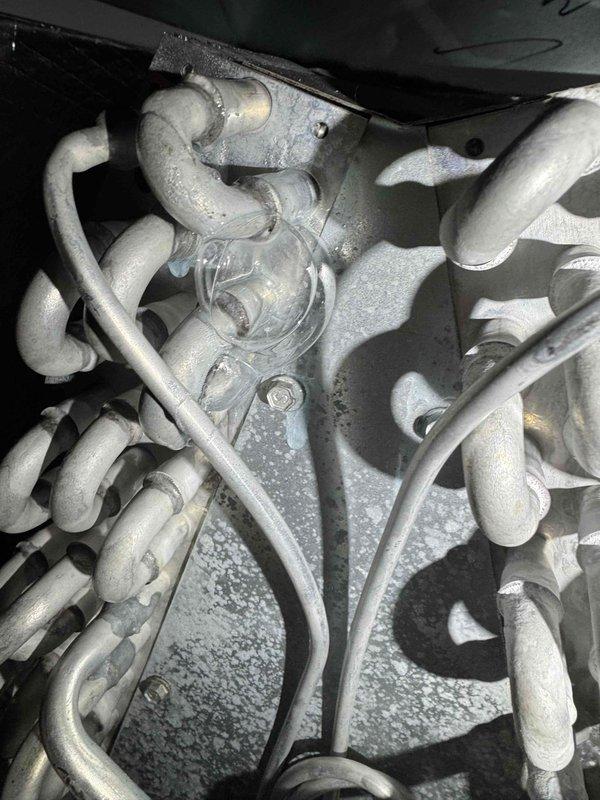 Responded to service call for 3-year-old A/C system struggling to maintain temperature, with unit set to 70°F but indoor temperature reaching 80°F. Upon arrival, found evaporator coil and refrigerant lines severely frozen with substantial ice buildup throughout the system. Documented frozen coil condition with photos showing complete frost coverage on copper tubing, expansion device, and surrounding components. Instructed system shutdown to allow complete ice melt before diagnostics could proceed, as frozen conditions prevent accurate assessment of underlying issues such as potential low refrigerant charge, restricted airflow, or failed blower motor.