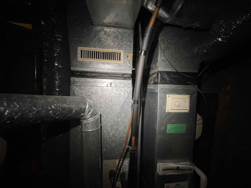 Performed on-site assessment of 16-year-old residential air conditioning system with reported failed outdoor unit. Inspected existing Goodman furnace, Space-Gard high efficiency air cleaner, ductwork configuration, and refrigerant line routing in basement utility area. Documented current system layout including galvanized metal plenum, flexible insulated ductwork, copper refrigerant lines, and floor-mounted air handler to provide comprehensive replacement estimate for complete AC system.