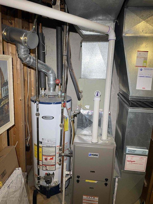 Conducted on-site evaluation of existing 16-year-old air conditioning system and 15-year-old water heater for replacement estimate. Documented current York furnace installation, water heater configuration with copper piping and gas connections, and existing PVC drainage and venting systems in basement mechanical room. Assessed equipment condition, measured installation area, photographed current setup including ductwork connections and utility configurations to provide comprehensive replacement proposal for both HVAC cooling system and water heating equipment.