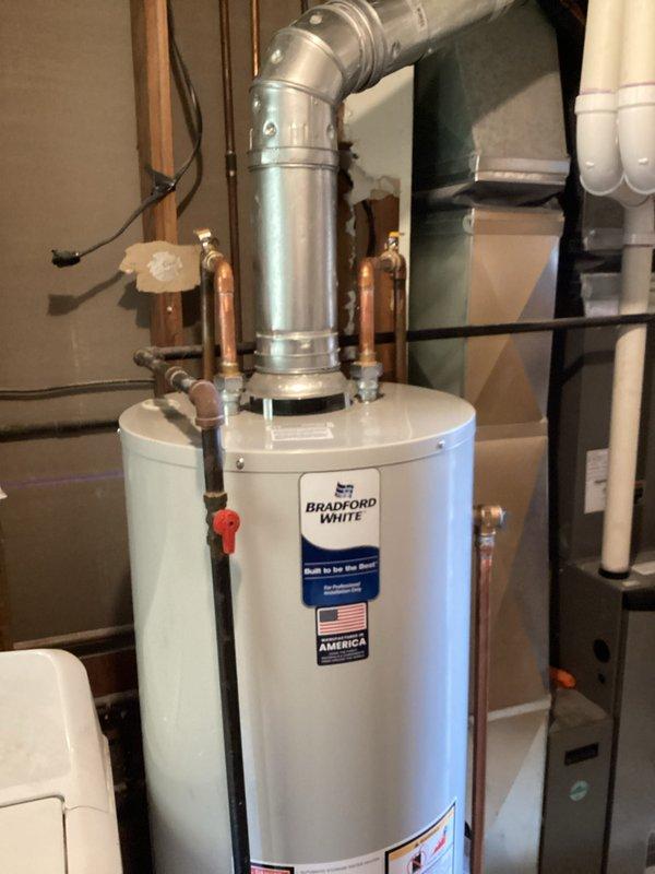 Completed full water heater replacement by draining and removing the existing unit, disposing of old equipment, and installing a new Bradford White RG240T6N tanked water heater. Installation included two dielectric unions to prevent galvanic corrosion between dissimilar metals, a new temperature and pressure relief valve for safety compliance, and six feet of single wall flue pipe with two 90-degree elbows for proper venting. Reconnected water supply lines using two 3/4-inch slip couplings and verified all connections for proper operation and leak-free performance.