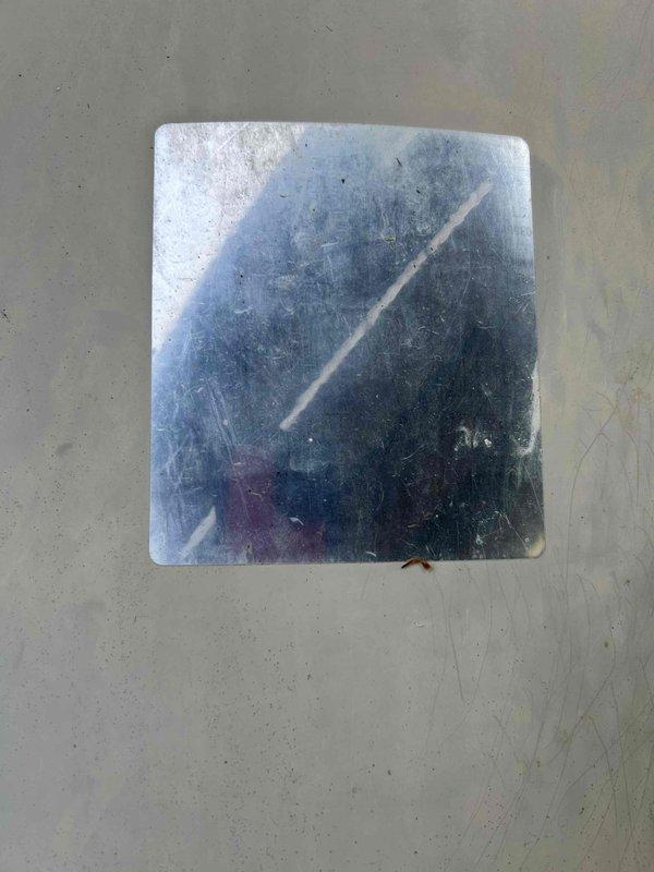 Responded to no cooling call on central air conditioning system over 15 years old. Upon arrival, located outdoor condensing unit installed beneath deck structure in recessed area. Performed diagnostic evaluation of system components and documented equipment condition with photos showing cylindrical condenser with copper fan guard, black vertical fins, refrigerant lines, and electrical disconnect box mounted on wooden framing.