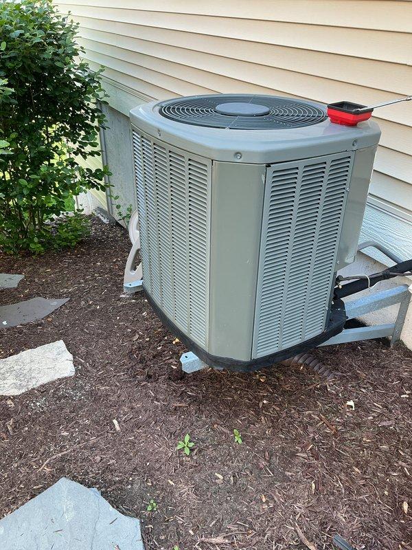 Completed promotional air conditioning tune-up on 11-year-old system with outdoor condenser unit located in landscaped area against exterior wall. Performed comprehensive inspection including condenser unit evaluation, thermostat functionality check, humidifier assessment, and hot water tank inspection. All components operating within normal parameters with no immediate service needs identified at time of inspection.