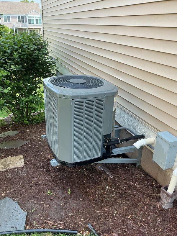 Completed promotional air conditioning tune-up on 11-year-old system with outdoor condenser unit located in landscaped area against exterior wall. Performed comprehensive inspection including condenser unit evaluation, thermostat functionality check, humidifier assessment, and hot water tank inspection. All components operating within normal parameters with no immediate service needs identified at time of inspection.