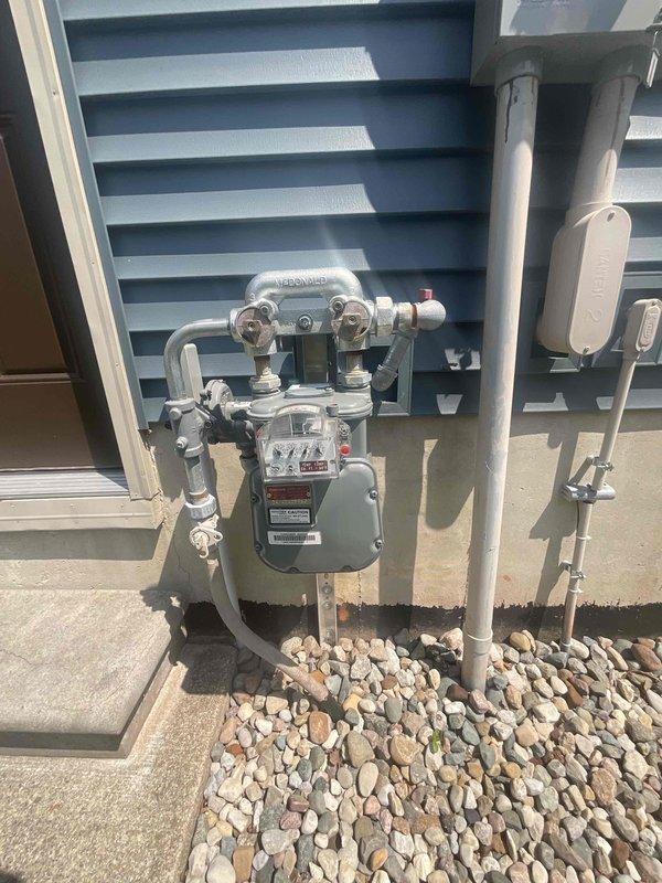 Conducted on-site evaluation for whole house generator installation at a 40-year-old residential property with no existing backup power system. Assessed existing electrical service panel to determine capacity and compatibility for generator integration, documenting current breaker configuration and available space for transfer switch installation. Evaluated exterior gas meter location and existing utility infrastructure to determine optimal generator placement and fuel source connection points. Photographed gas meter assembly, including shut-off valves and piping configuration, to plan natural gas line extension requirements. Documented electrical panel specifications and circuit layout to design appropriate automatic transfer switch system for seamless power transition during outages.