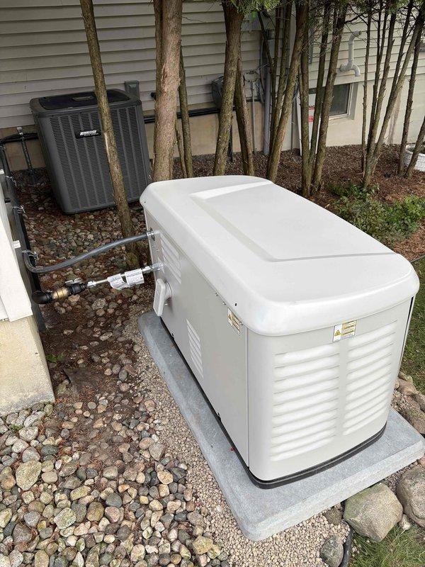 Completed installation of Generac 14kW standby generator with 200-amp automatic transfer switch on concrete pad with proper clearances from residential structure. Generator positioned alongside existing HVAC equipment with appropriate ventilation access, mounted on prepared concrete foundation surrounded by decorative landscaping stone. Electrical connections completed per manufacturer specifications and local code requirements. Permits obtained prior to installation, with electrical inspection coordinated and scheduled. All conduit runs installed from generator to transfer switch location, Service Finance paperwork processed and executed with identification documentation on file. Unit tested and operational upon completion.