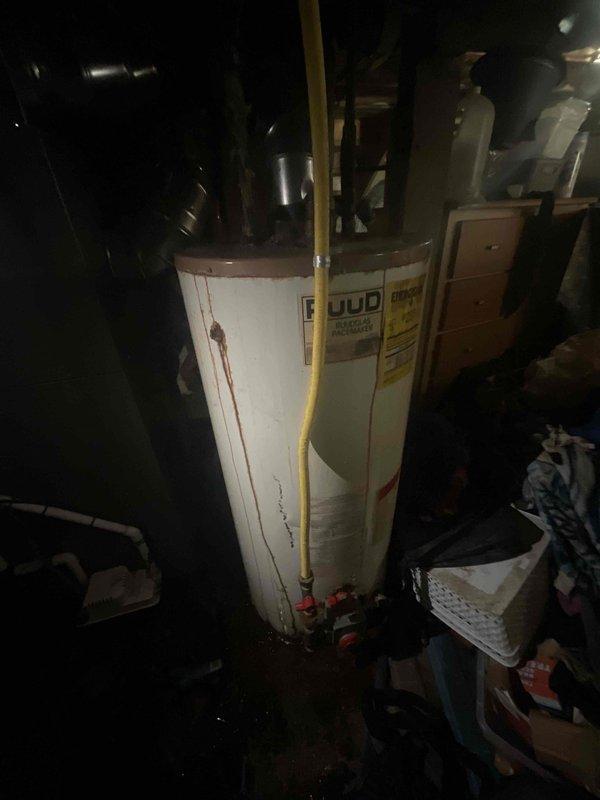 Conducted on-site evaluation of existing gas water heater in basement utility area. Upon inspection, unit displayed significant aging and deterioration including rust accumulation on tank top, heavy mineral deposits and corrosion on copper supply lines, and evidence of hard water scaling. Multiple copper pipes extending from tank top showed varying degrees of oxidation with white calcium buildup indicating potential past leaks or seepage. Water heater exhibited end-of-service-life conditions requiring full replacement. Documented equipment condition and surrounding installation area with photographs showing confined basement space with limited clearance, existing gas and water connections, and current venting configuration. Prepared comprehensive replacement estimate for new gas-fired water heater installation including removal and disposal of existing unit.
