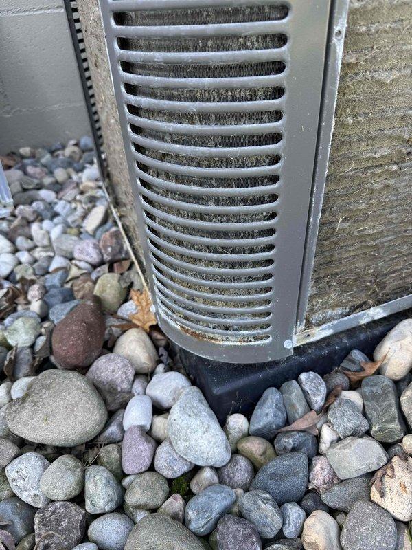 Responded to service call for AC unit not cooling properly on a two-year-old system. Upon inspection, discovered severely corroded copper refrigerant line with heavy oxidation and mineral deposits inside the ductwork, along with excessive moisture accumulation on interior duct surfaces. The corrosion indicates a refrigerant leak that has been ongoing, which explains the reduced cooling capacity. Documented the corroded line and moisture conditions with photos for record. Advised that the refrigerant line requires replacement and system will need proper refrigerant charge after repair is completed. Unit exterior shows normal wear for outdoor installation on rock bed foundation.