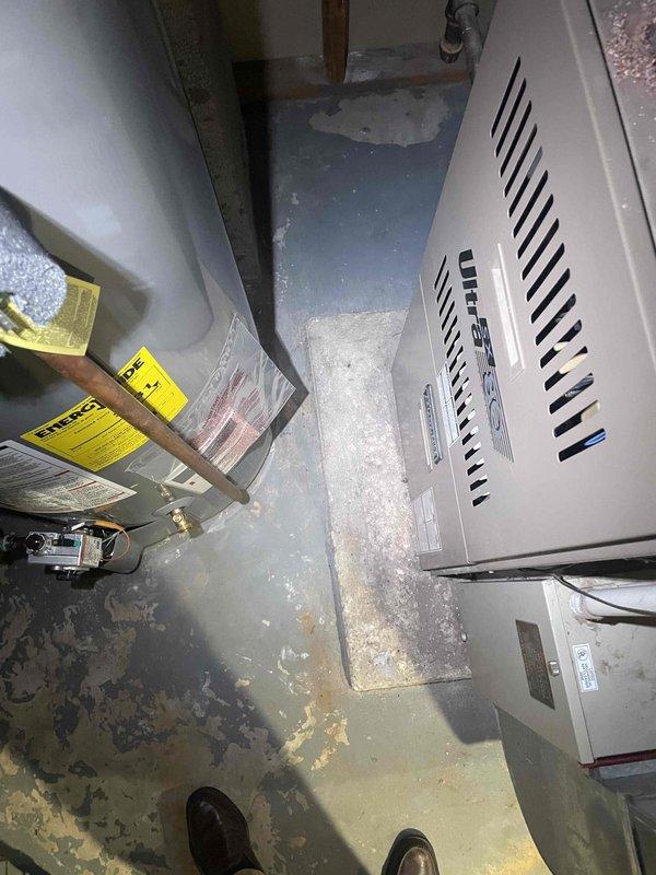 Conducted comprehensive assessment of basement-located HVAC system for replacement estimate including 30-year-old natural gas furnace and non-operational air conditioning unit of unknown age. Documented existing equipment condition, noting significant moisture damage and water staining on concrete floor surrounding units, and evaluated mechanical components, ductwork connections, and installation environment to provide accurate replacement specifications for complete furnace and AC system.