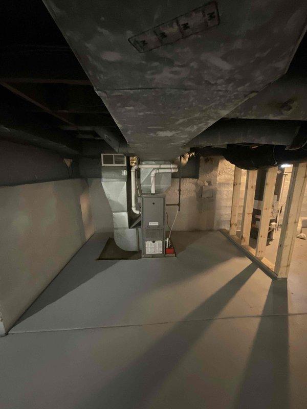 Completed site assessment for new mini-split installation in living room area. Evaluated basement mechanical space, documenting existing HVAC infrastructure including furnace, water heater, and ductwork configuration to determine optimal routing for refrigerant lines and condensate drainage. Confirmed structural conditions and available pathways for line set installation from exterior condenser location to interior air handler placement.
