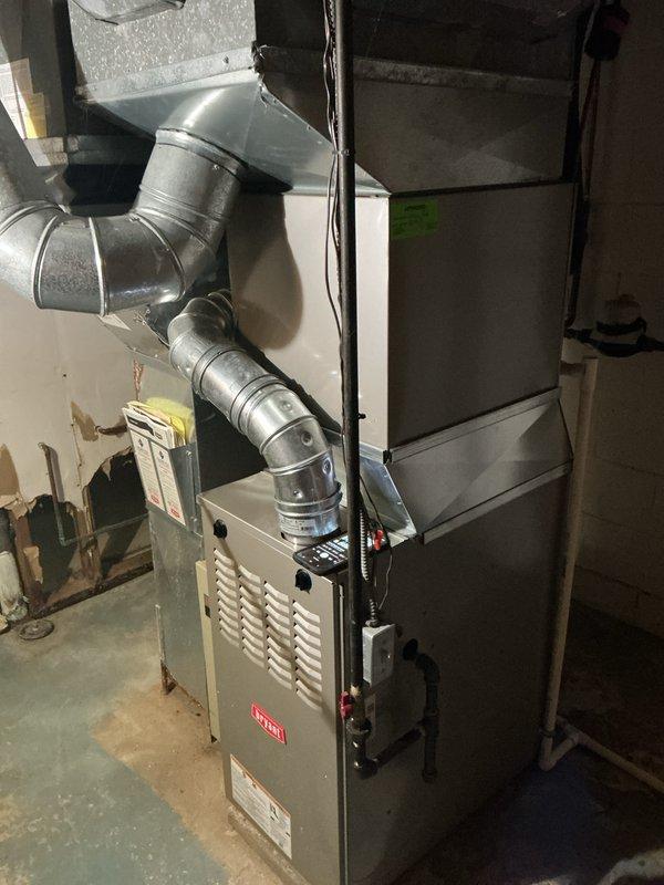 Completed annual cooling maintenance on Bryant HVAC system in basement utility area. Inspected furnace unit, air handler, ductwork connections, and condensate drain system with PVC piping and drain pan. Noted filter change required and documented system condition with photos showing metallic ductwork, electrical connections, and overall installation configuration.