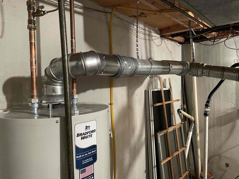 Successfully installed a 40-gallon Bradford White gas-fired water heater in basement utility area. Completed all necessary plumbing connections using copper piping with brass fittings and valves at supply and discharge points. Installed metallic vent ductwork with proper elbow configuration to ensure safe exhaust ventilation. Connected yellow gas line to unit's gas valve and verified all connections for proper operation and safety compliance.