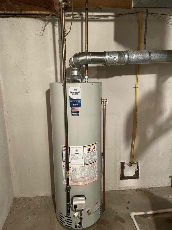 Successfully installed a 40-gallon Bradford White gas-fired water heater in basement utility area. Completed all necessary plumbing connections using copper piping with brass fittings and valves at supply and discharge points. Installed metallic vent ductwork with proper elbow configuration to ensure safe exhaust ventilation. Connected yellow gas line to unit's gas valve and verified all connections for proper operation and safety compliance.