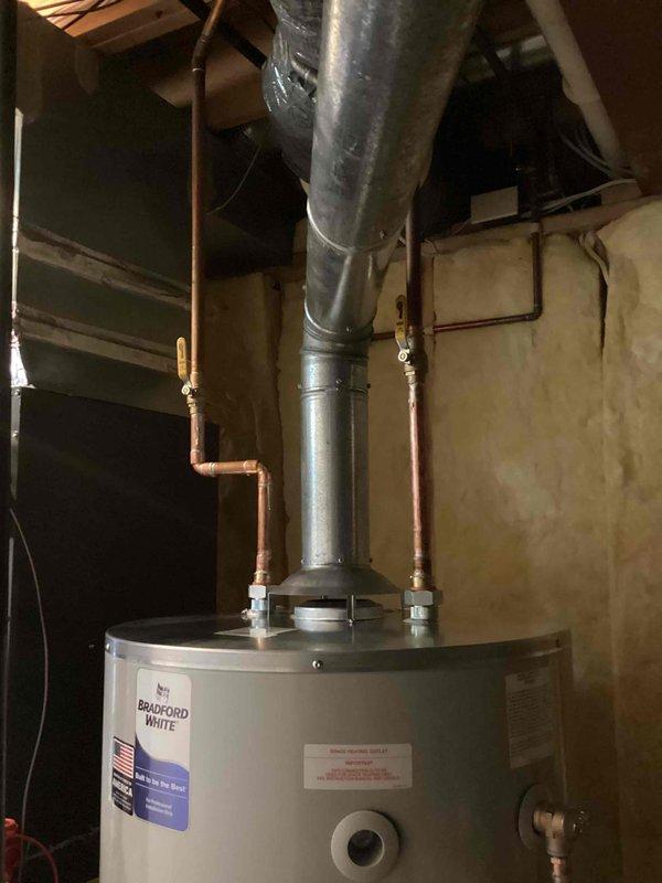 Successfully installed a 75-gallon Bradford White tanked water heater in basement utility area. Completed all necessary plumbing connections including copper supply lines with shut-off valves, proper venting with metallic vent pipe extending to code-compliant termination point, and reconnection of all water supply systems. Installation performed in accordance with mechanical permit requirements and manufacturer specifications.