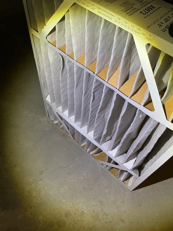 Completed annual cooling maintenance on residential HVAC system. Performed comprehensive inspection of air handler unit, verified proper operation of all components, and inspected existing air filter condition. Filter showed normal wear pattern with intact mesh structure and even distribution throughout the media. Documented equipment condition with photos showing filter installation within black metal housing and available replacement filters on-site. System operating within normal parameters with no immediate service needs identified.