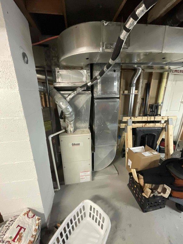 Provided estimate for complete HVAC system replacement including outdoor air conditioning condenser unit and basement-installed Gibson furnace. Existing equipment is over 15 years old and non-operational, with outdoor condenser showing significant rust deterioration on top surface. Assessment included evaluation of current ductwork configuration with flexible metallic ducting connecting floor-mounted furnace to overhead plenum system in basement utility area.