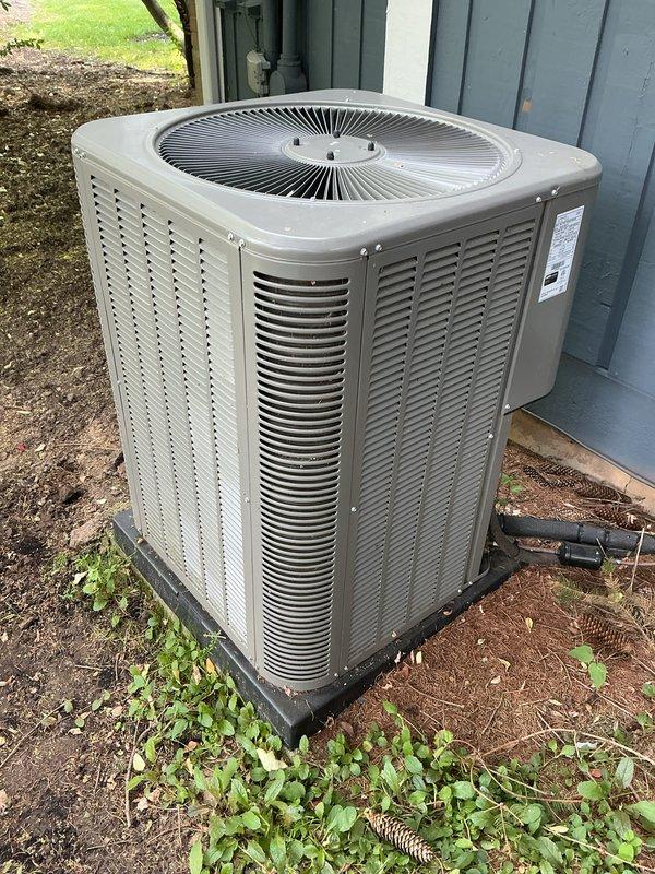 Completed annual cooling maintenance on residential HVAC system. Inspected indoor air handler unit and replaced furnace filter with new mesh filter panel installed in metal frame housing. Verified proper airflow through ductwork and connections. Proceeded to outdoor condensing unit for exterior inspection. Examined beige AC unit mounted on plastic pad against building foundation. Inspected fan grille, louvered vents, and refrigerant line connections. Verified electrical conduit routing and manufacturer specifications. Confirmed unit operating within normal parameters with no visible signs of damage or wear. All components functioning properly upon completion of maintenance service. Wore shoe covers per customer request throughout interior portion of service call.