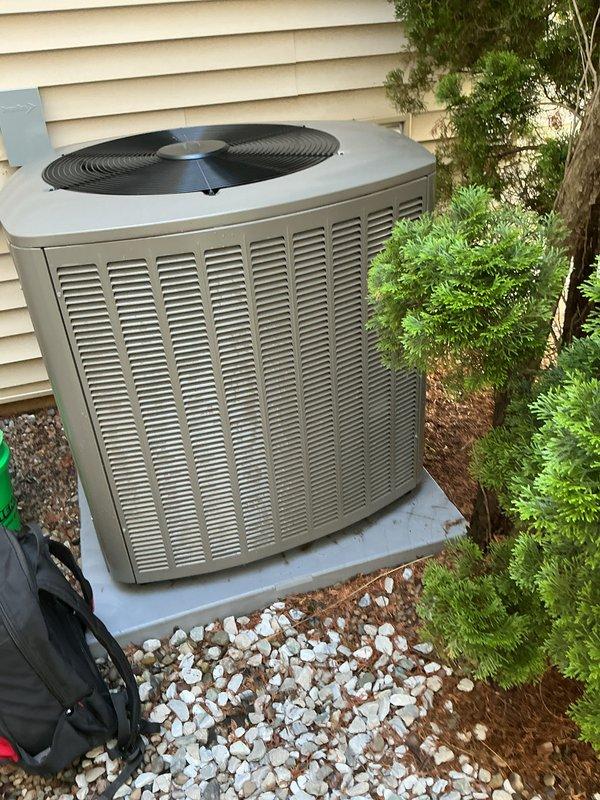 Completed scheduled air conditioning maintenance on residential system less than one year old. Performed comprehensive tune-up including inspection of outdoor condenser unit, verified proper operation of all components, checked refrigerant levels, cleaned condenser coils, inspected electrical connections, and tested system performance. Unit found operating within manufacturer specifications with no issues identified. Documented equipment condition with photographs showing well-maintained exterior installation on concrete pad with adequate clearance from landscaping.