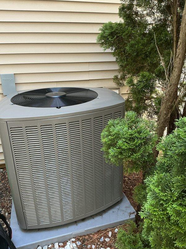 Completed scheduled air conditioning maintenance on residential system less than one year old. Performed comprehensive tune-up including inspection of outdoor condenser unit, verified proper operation of all components, checked refrigerant levels, cleaned condenser coils, inspected electrical connections, and tested system performance. Unit found operating within manufacturer specifications with no issues identified. Documented equipment condition with photographs showing well-maintained exterior installation on concrete pad with adequate clearance from landscaping.